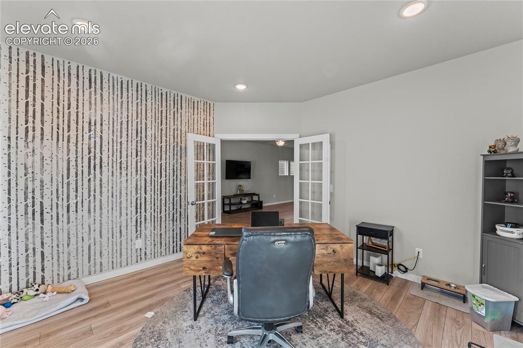 Image 9 of 17: Recessed lighting, wood-finish flooring, accent wall, French doors, built-i