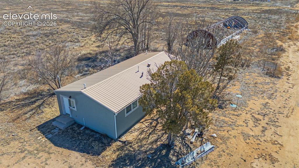 Caption: Single-story residence with a metal roof and light gray siding