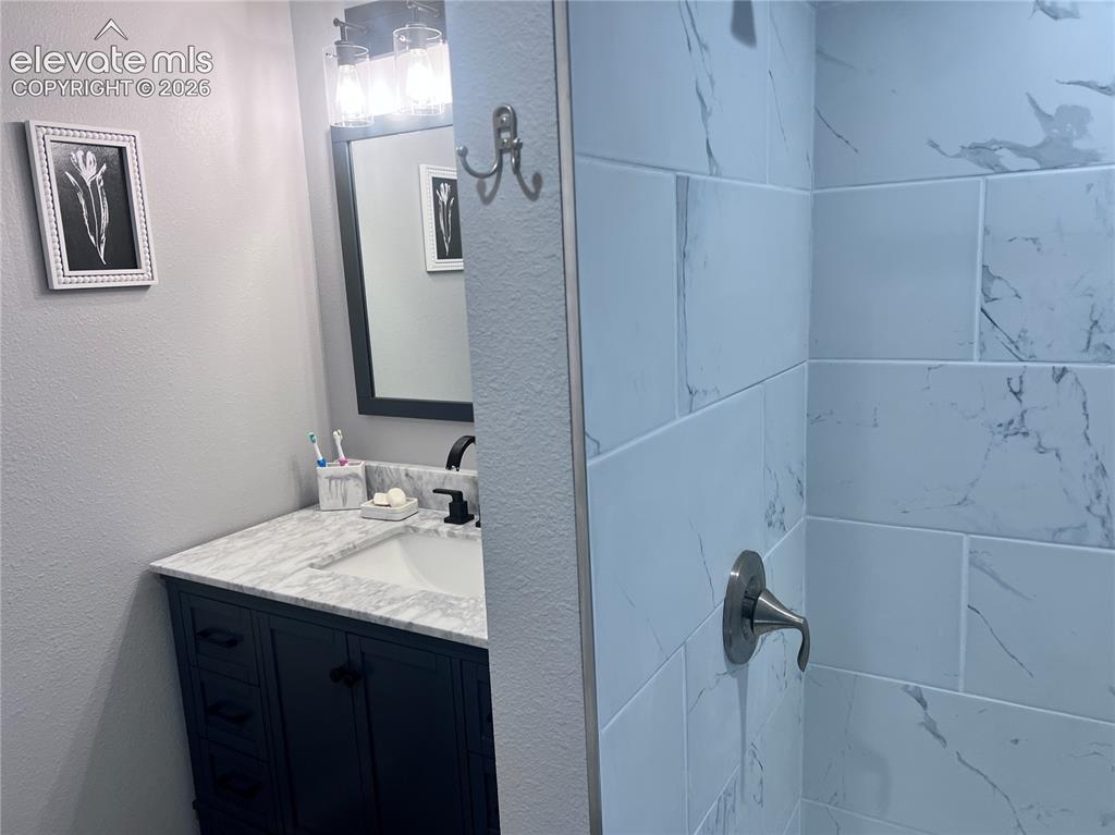 Image 19 of 49: Vanity with a marble-finish countertop, undermount sink, and dark cabinetry