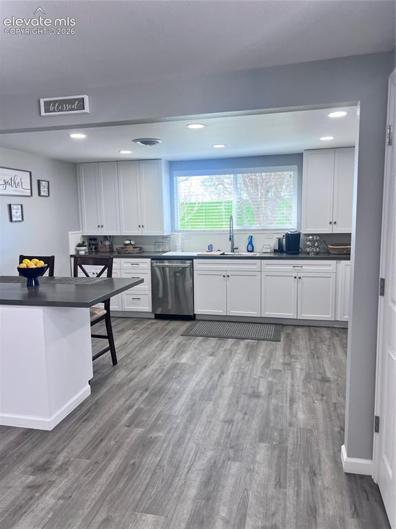 Image 22 of 49: Kitchen featuring white cabinetry, a large window, stainless steel dishwash