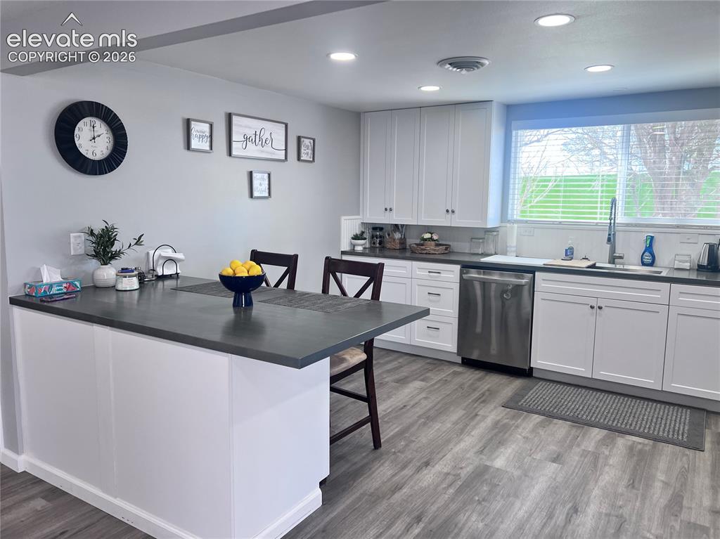 Image 27 of 49: Kitchen featuring white cabinetry, wood-finish flooring, recessed lighting,