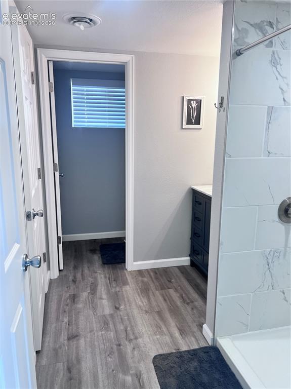 Image 3 of 49: Wood-finish flooring throughout, shower with white tiled walls, and a dark 