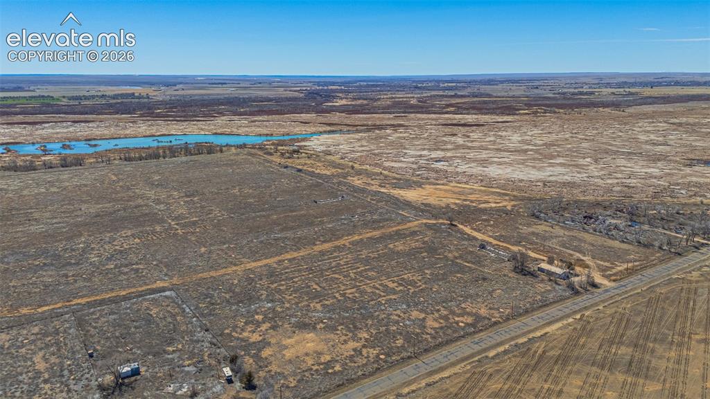 Image 37 of 49: Expansive land parcel featuring open fields, a natural water body, and an e