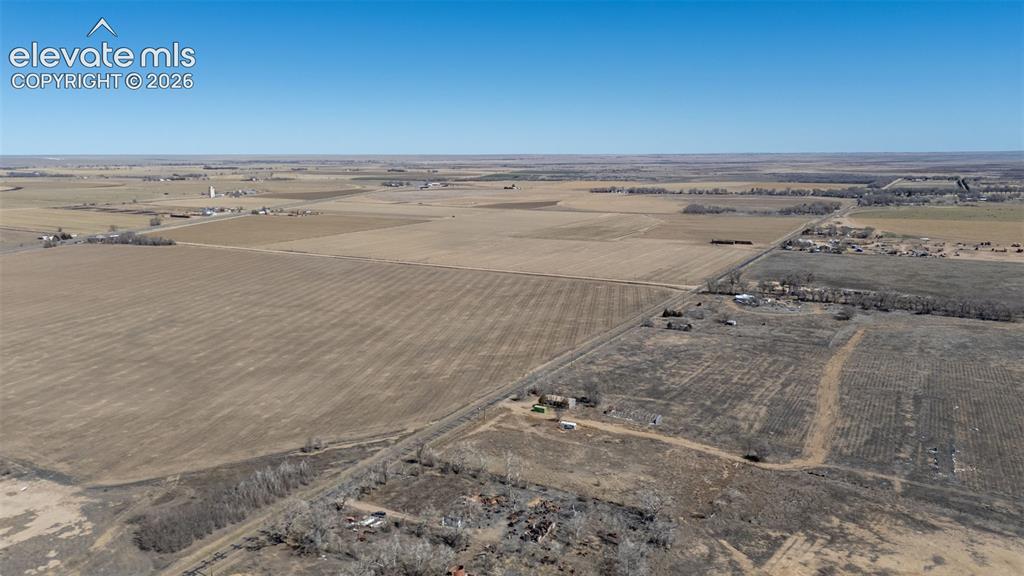 Image 38 of 49: Expansive land parcel featuring agricultural fields and scattered structure