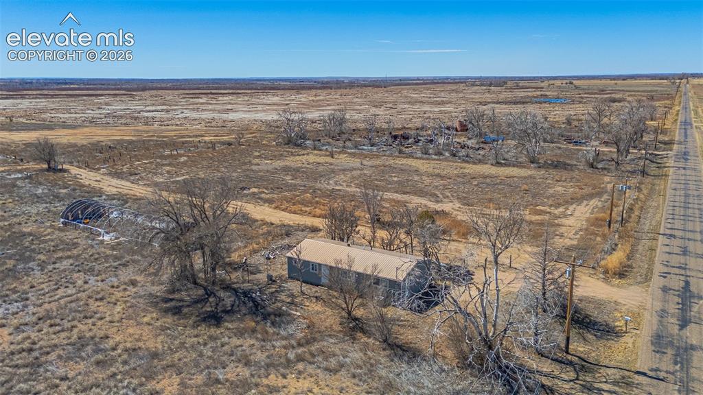 Image 44 of 49: Expansive undeveloped land featuring a residential structure and a hoop hou