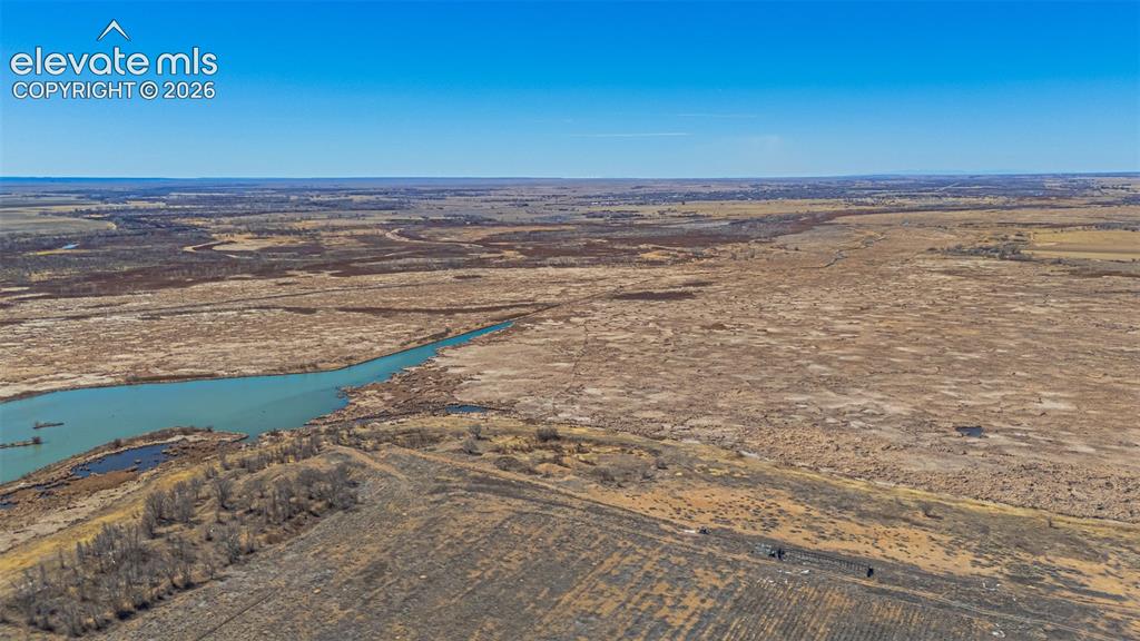 Image 45 of 49: Expansive open landscape with a prominent waterway and distant natural terr