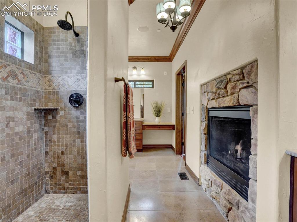 Image 30 of 37: Primary bathroom with  dual fireplace between bed and bath