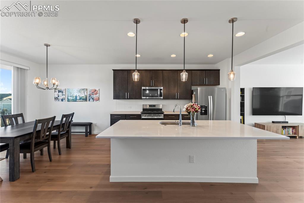 Image 12 of 31: Kitchen featuring hanging light fixtures, decorative backsplash, stainless