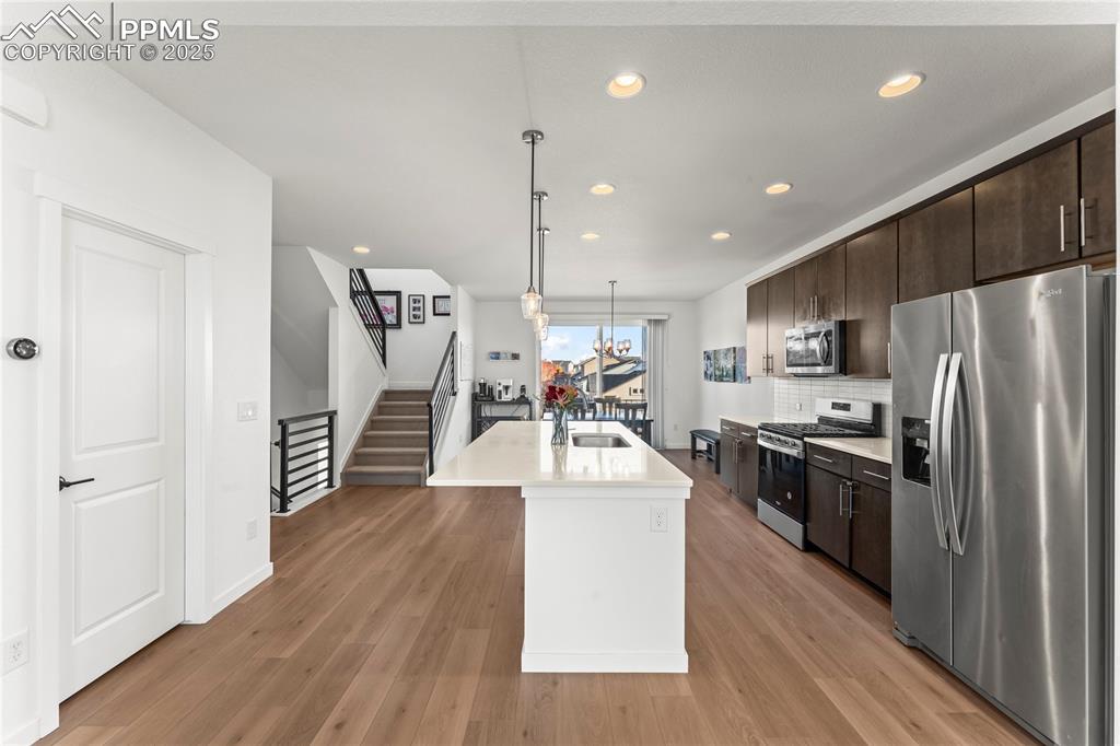 Image 13 of 31: Kitchen with stainless steel appliances, dark brown cabinetry, recessed lig