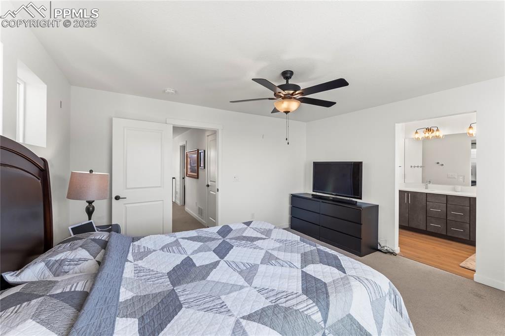 Image 21 of 31: Bedroom with ensuite bathroom, carpet, and a ceiling fan