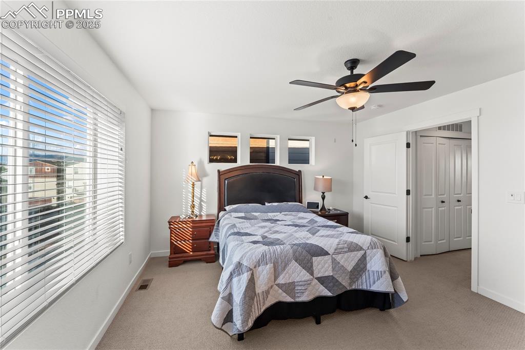 Image 22 of 31: Bedroom featuring light colored carpet, multiple windows, and a ceiling fan