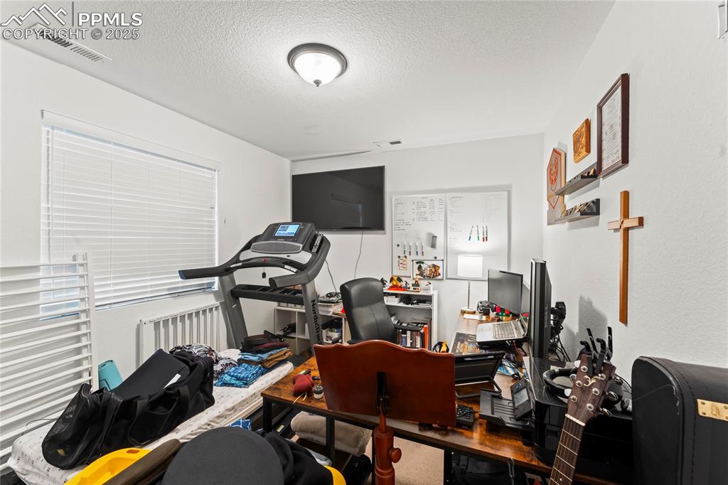 Image 28 of 31: Home office featuring a textured ceiling and radiator heating unit