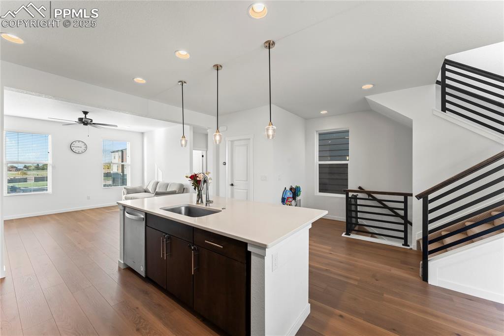 Image 5 of 31: Kitchen with dark brown cabinetry, open floor plan, an island with sink, da