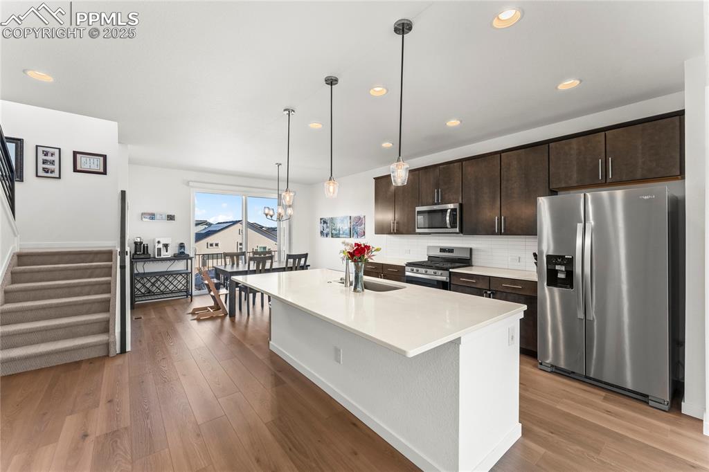 Image 6 of 31: Kitchen featuring stainless steel appliances, dark brown cabinetry, a kitch