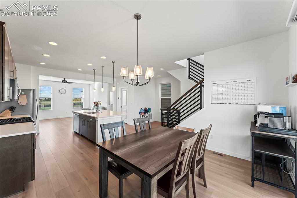 Image 8 of 31: Dining area featuring light wood-style flooring, stairs, ceiling fan, a cha