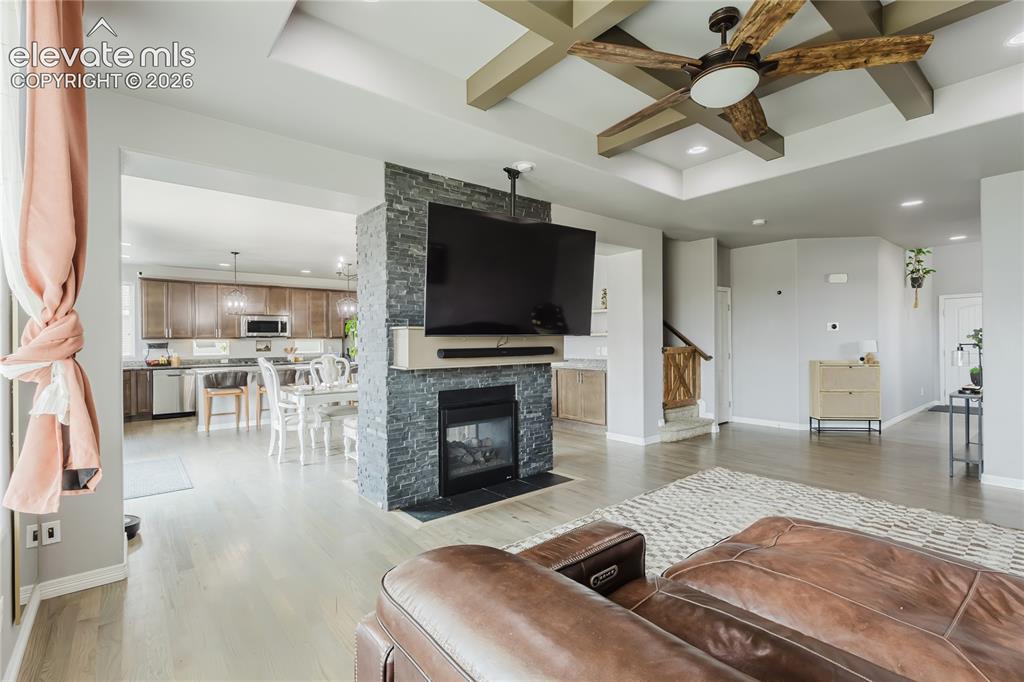 Image 10 of 46: Open-concept living area featuring wood-finish flooring and a coffered ceil
