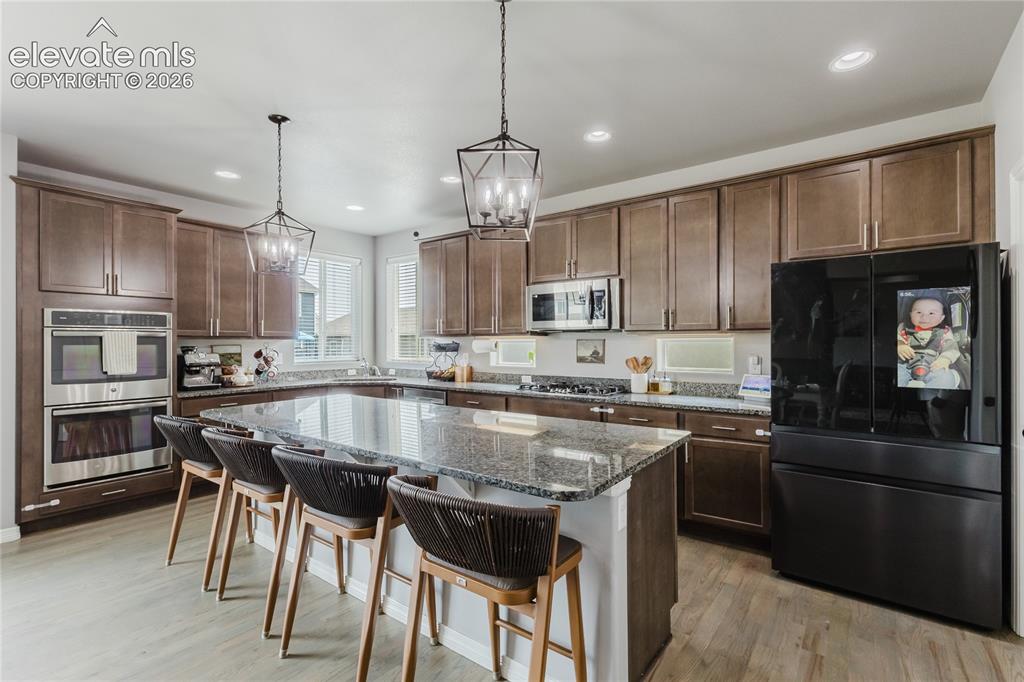 Image 14 of 46: Spacious kitchen featuring a large island with a stone countertop, built-in