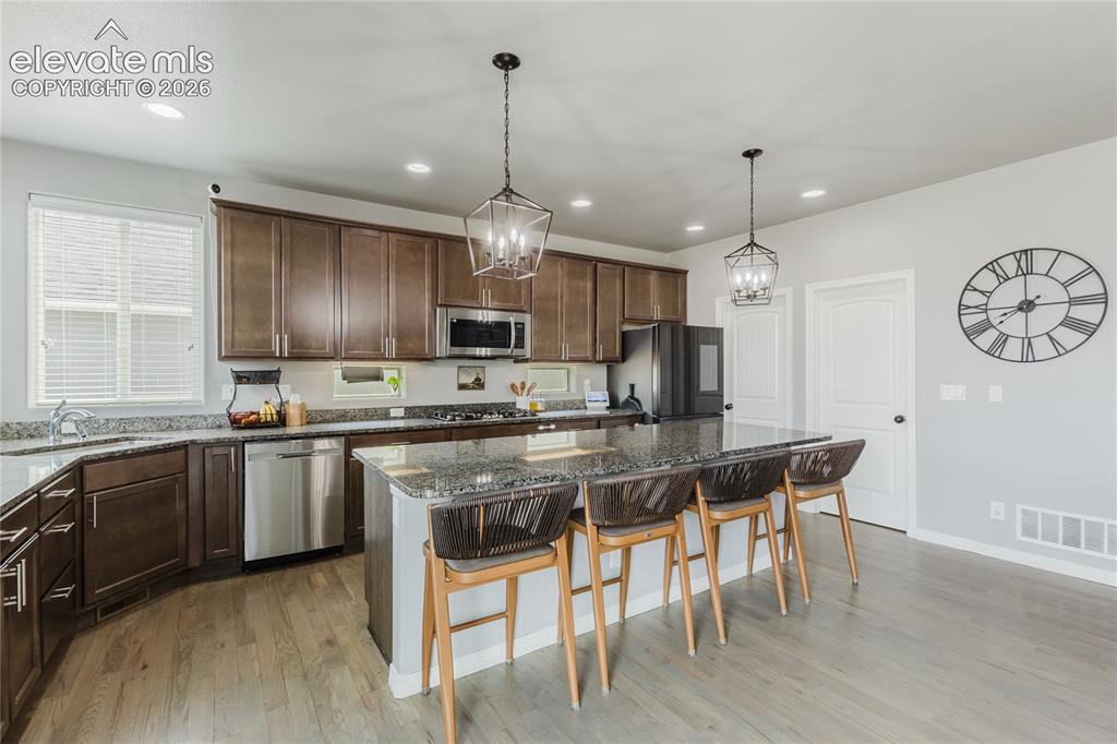 Image 15 of 46: Contemporary kitchen featuring wood-finish flooring and a central island wi