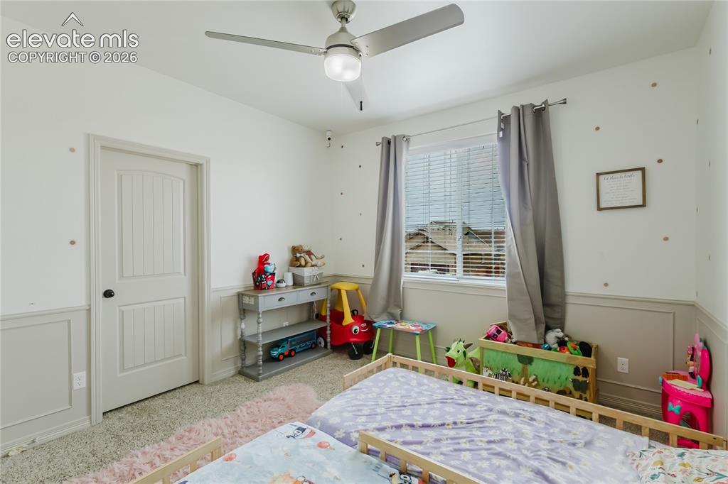 Image 24 of 46: Carpeted interior room featuring wainscoting, a ceiling fan with integrated
