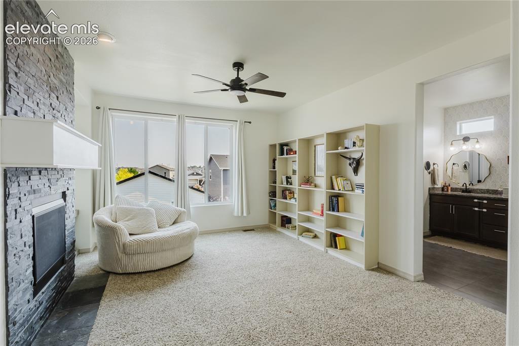 Image 31 of 46: Spacious room featuring a stone-clad fireplace with a white mantel, multipl