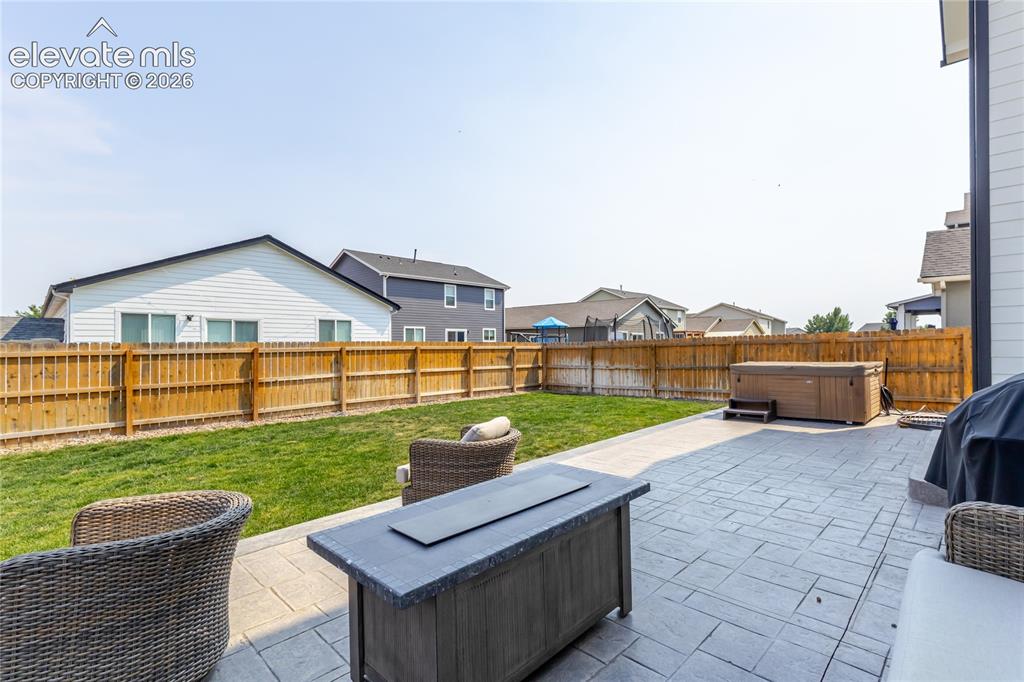 Image 40 of 46: Spacious backyard featuring a stamped concrete patio, a hot tub with steps,