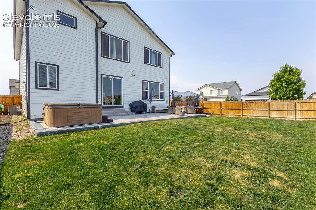 Image 43 of 46: Expansive backyard featuring a manicured lawn and a concrete patio