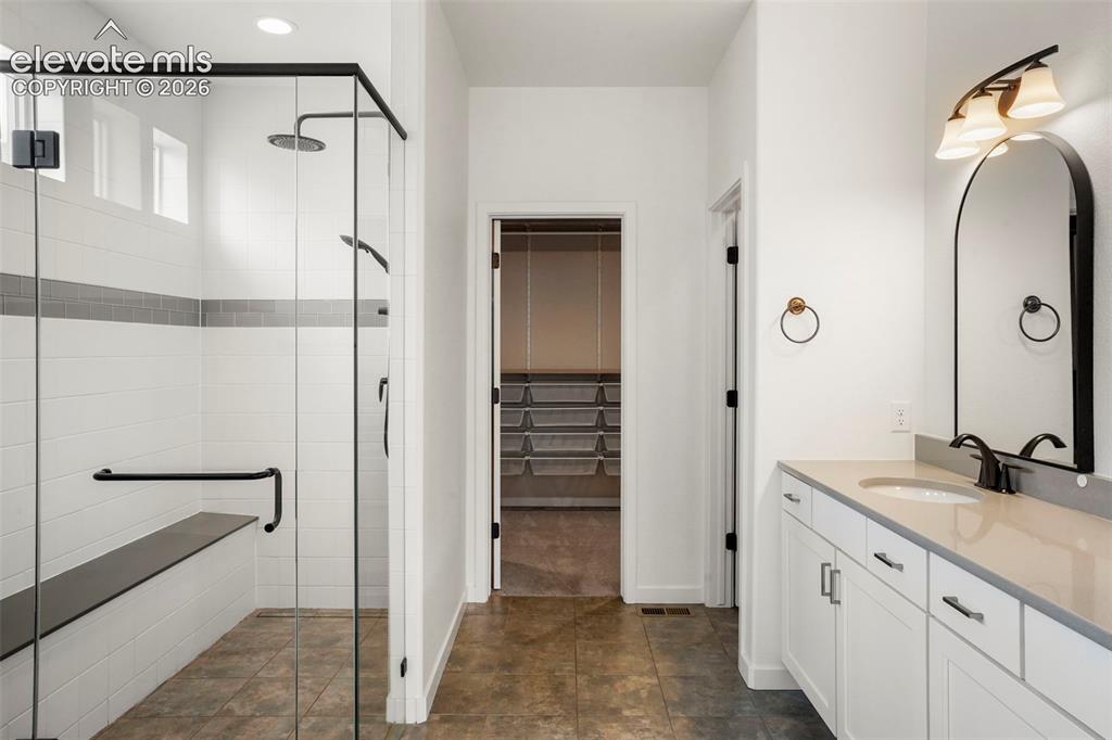 Image 17 of 37: Walk-in shower with a glass enclosure, built-in bench, and black fixtures