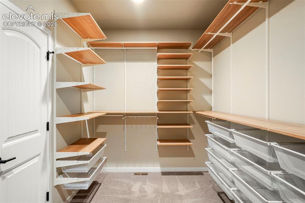 Image 18 of 37: Custom closet system featuring wood-finish shelving, wire mesh drawers, and