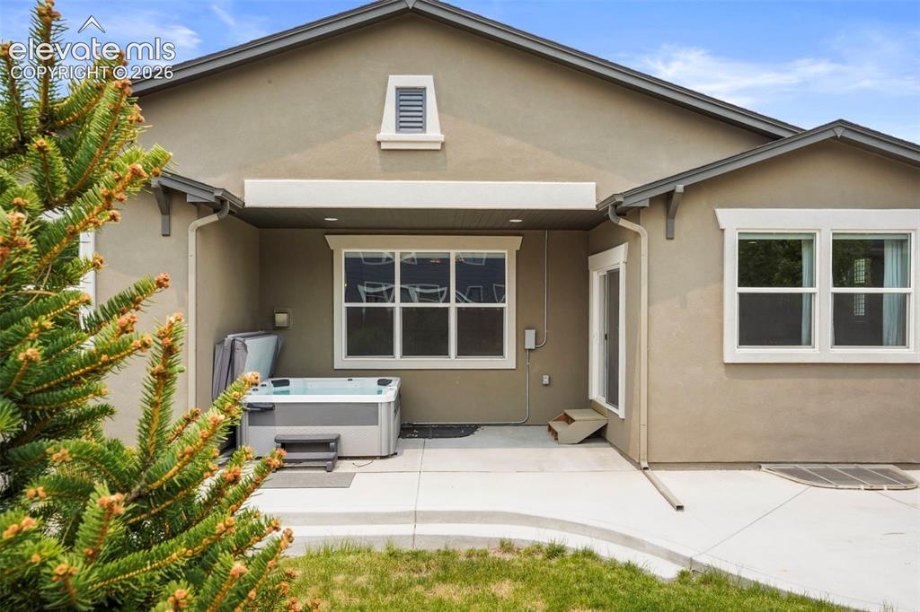 Image 28 of 37: Patio area featuring a hot tub, concrete surfacing, and stucco exterior