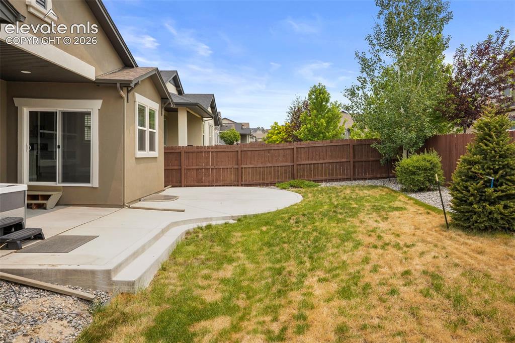 Image 29 of 37: Expansive backyard featuring a concrete patio, a privacy fence, and mature 