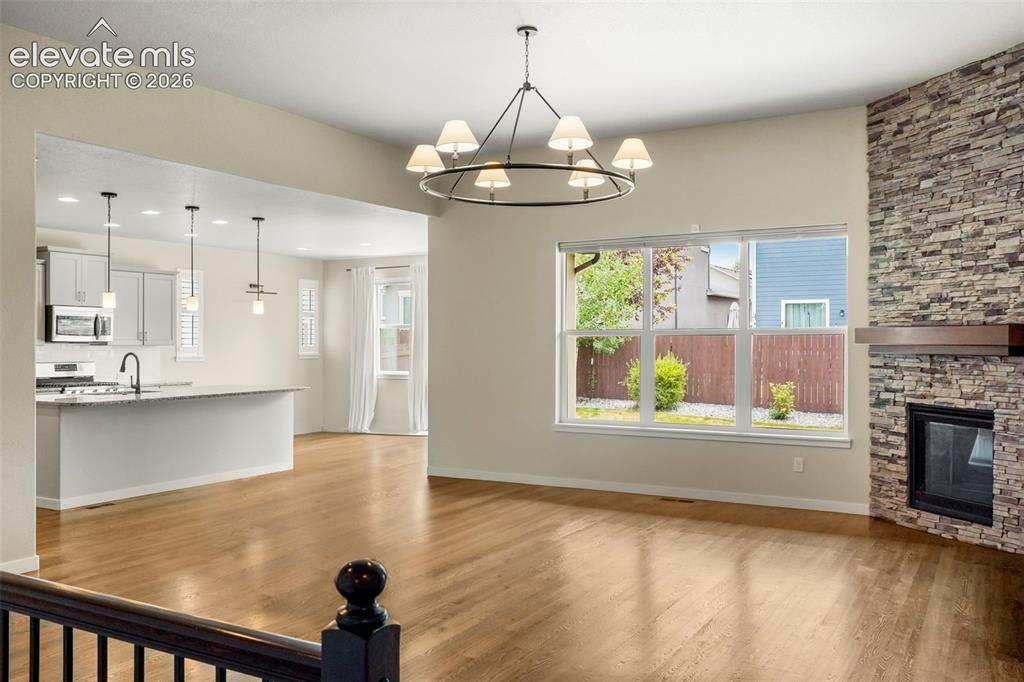 Image 4 of 37: Expansive living area featuring wood-finish flooring and a stone-clad firep