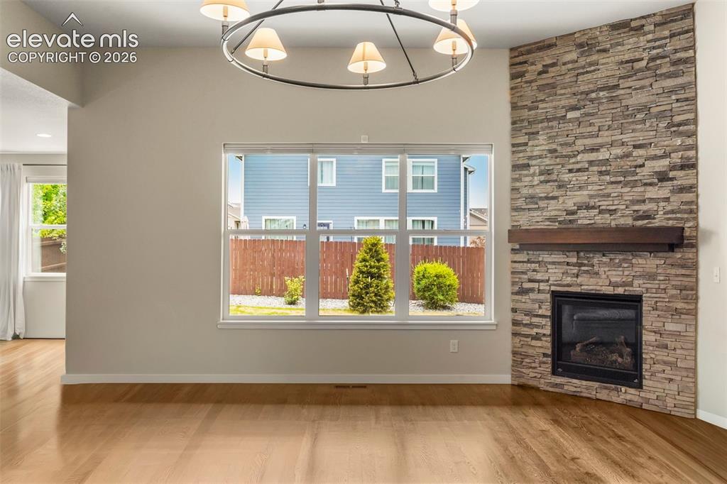 Image 5 of 37: Spacious room featuring wood-finish flooring and a stone-clad fireplace wit