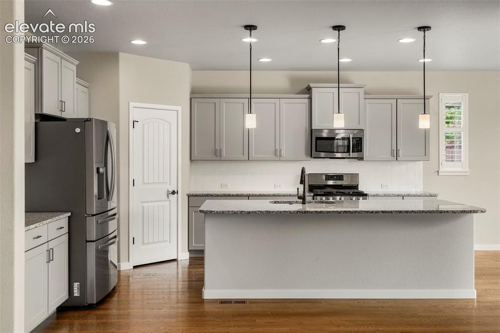 Image 7 of 37: Open-concept kitchen featuring light-toned cabinetry, granite countertops, 
