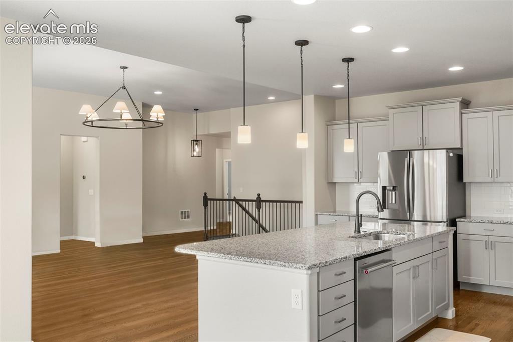 Image 9 of 37: Kitchen island featuring a stainless steel sink, pull-down faucet, and gran