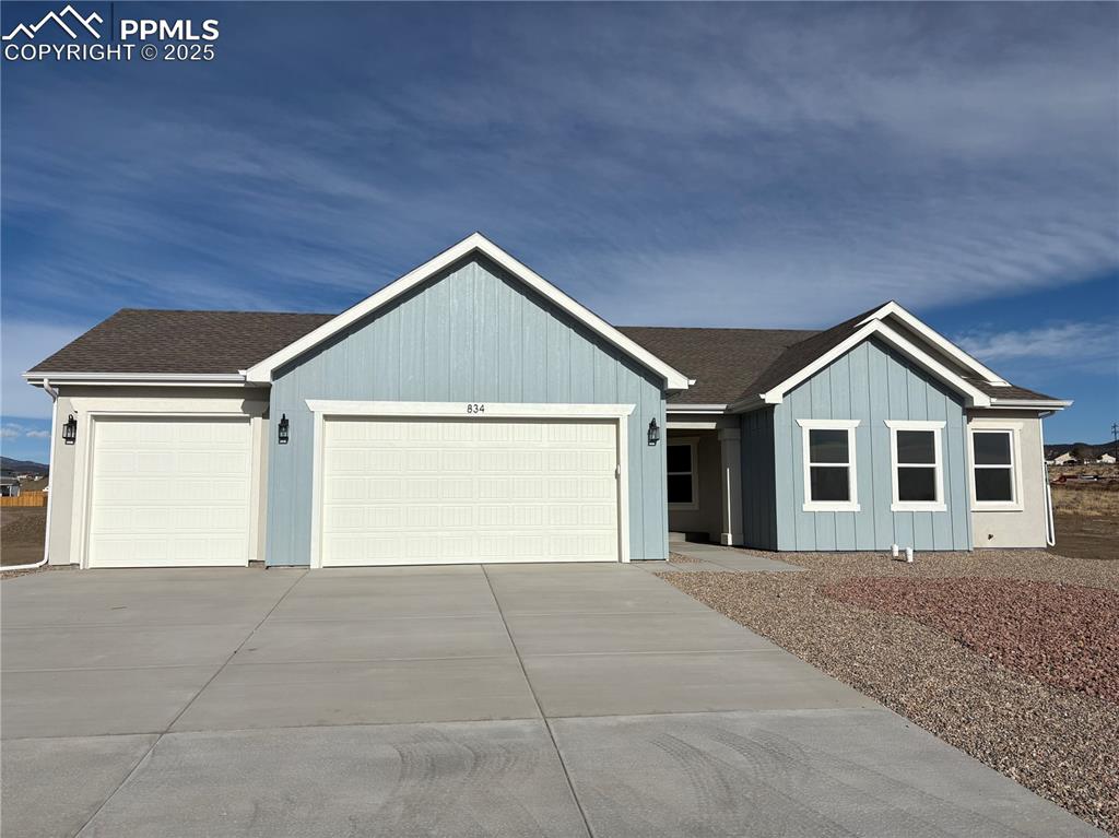 Caption: Ranch-style home with a shingled roof, driveway, and a garage