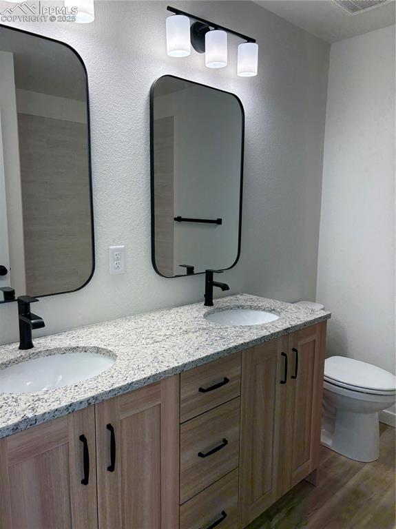 Image 19 of 22: Bathroom with double vanity and dark wood-style floors