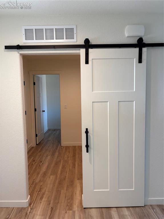 Image 3 of 22: Hall with a barn door and light wood-style floors