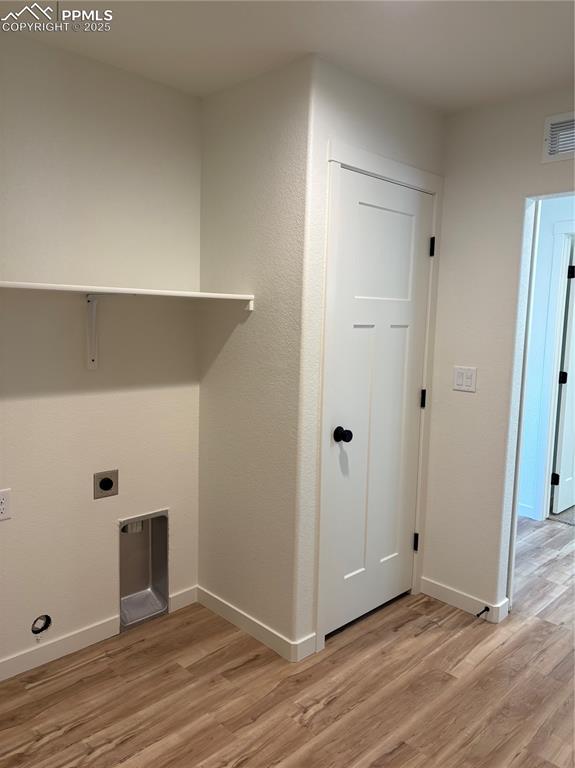 Image 4 of 22: Washroom with light wood-type flooring and hookup for an electric dryer