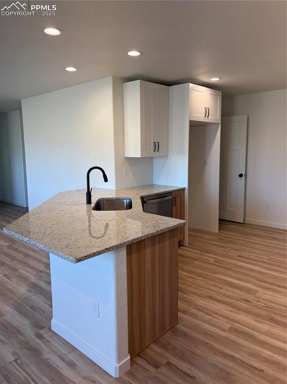 Image 8 of 22: Kitchen featuring white cabinetry, light stone counters, a peninsula, reces