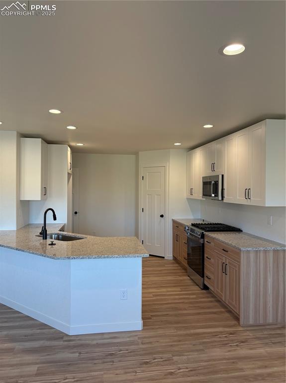 Image 9 of 22: Kitchen with light stone countertops, stainless steel appliances, light woo