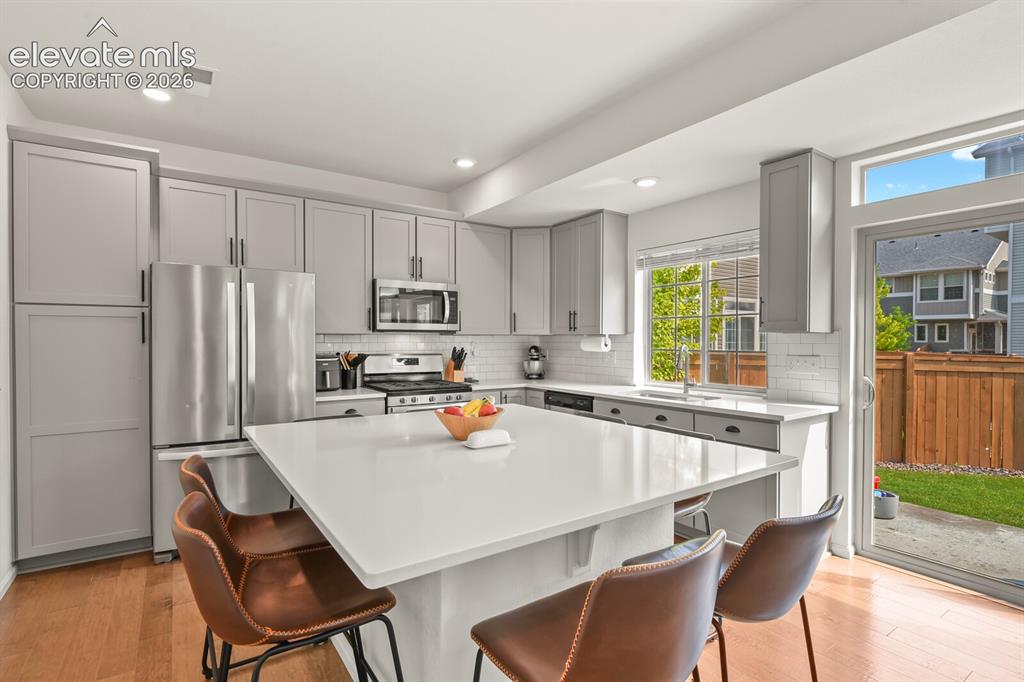 Image 10 of 31: Bright kitchen featuring a substantial central island with seating, stainle