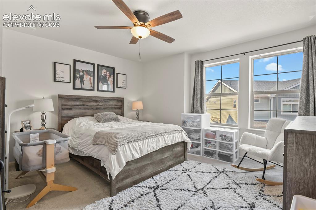 Image 15 of 31: Spacious primary bedroom featuring dual windows, a ceiling fan with integra