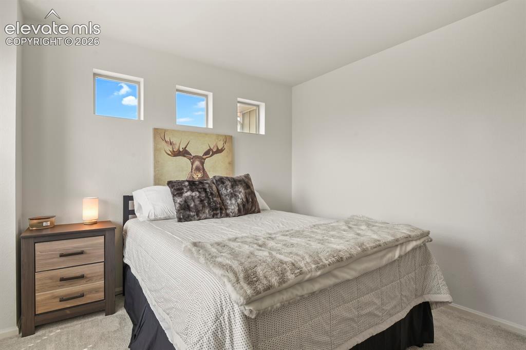 Image 21 of 31: Bedroom #3. Featuring three high-set windows, light gray walls and gray car