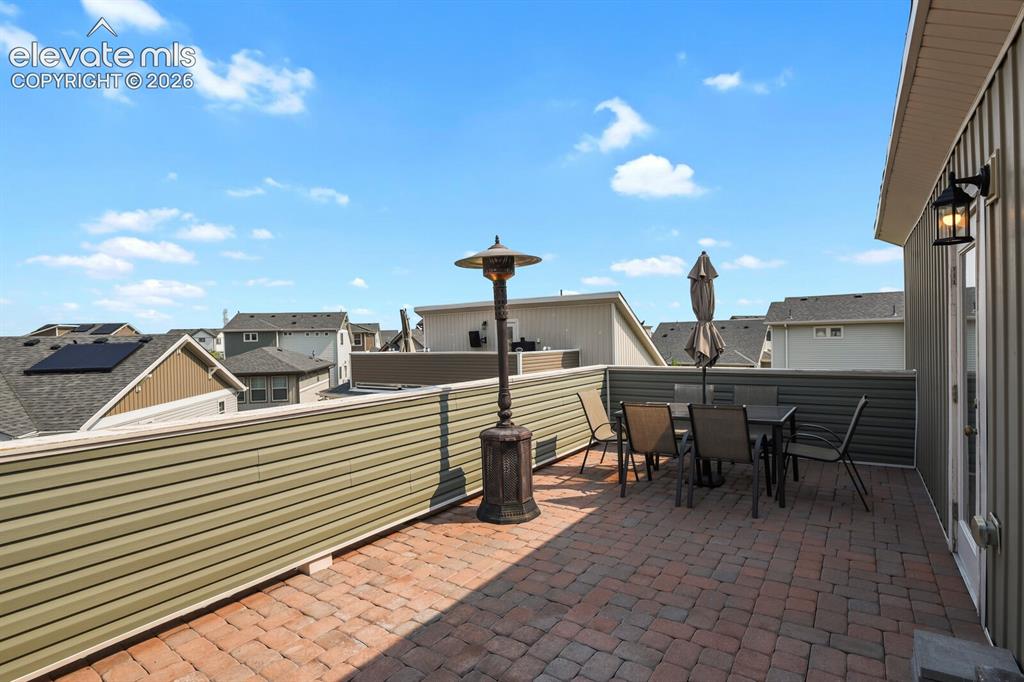 Image 25 of 31: Expansive rooftop deck featuring brick paver flooring, a robust privacy wal