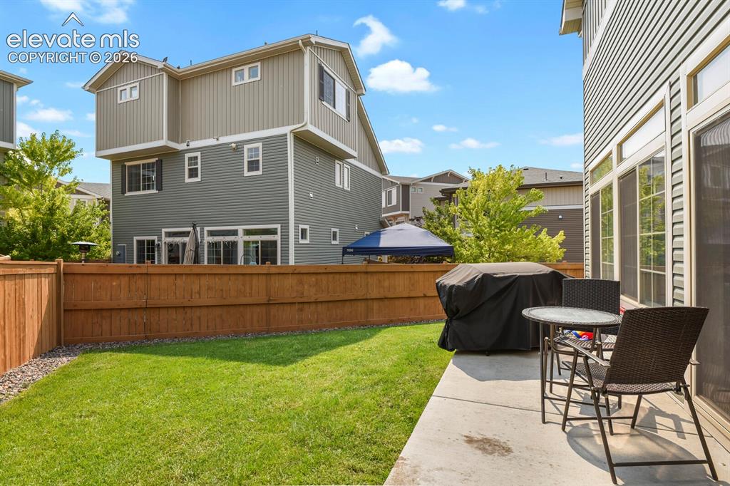 Image 26 of 31: Private backyard featuring a concrete patio, green lawn and wood privacy fe