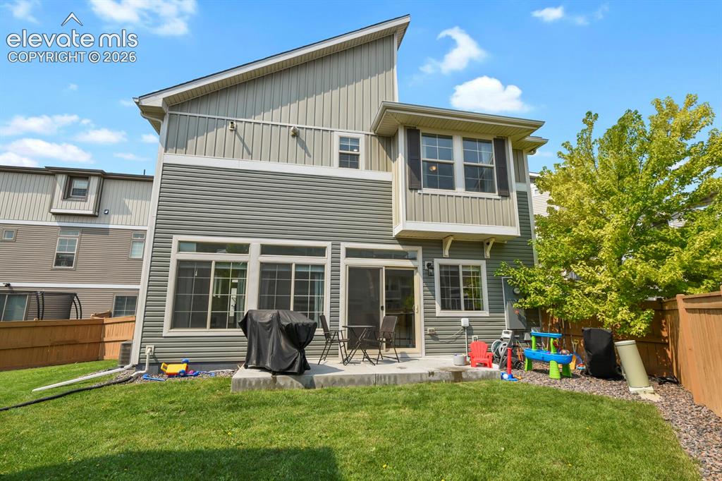 Image 28 of 31: Rear exterior with a concrete patio and a manicured lawn