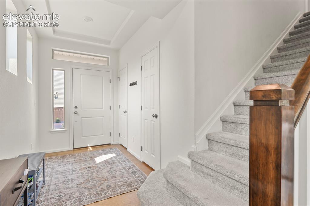 Image 3 of 31: Entryway featuring a white paneled door with transom and side windows, wood