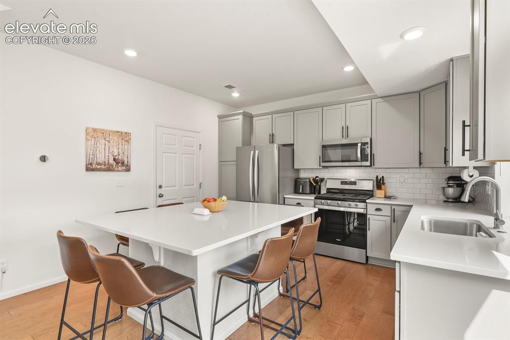 Image 9 of 31: Kitchen featuring a central island with white quartz countertop, light gray