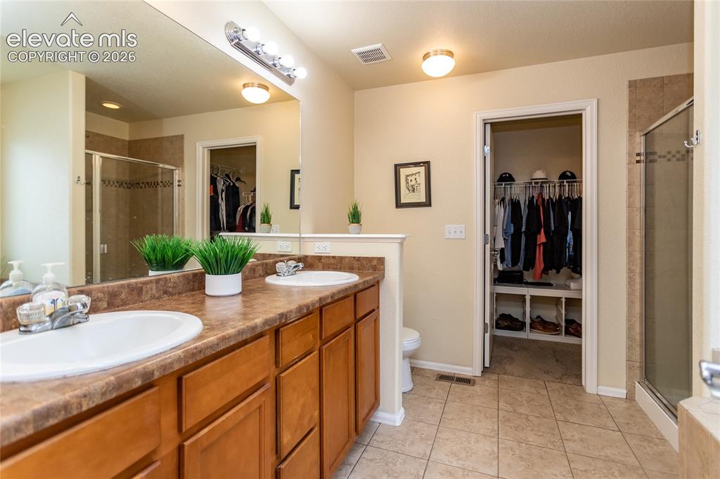Image 18 of 49: Primary bathroom offers extended vanity with double sinks.