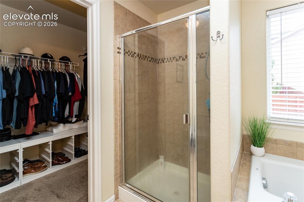 Image 20 of 49: Primary bathroom offers an oversized shower with tile surround. Walk-in clo